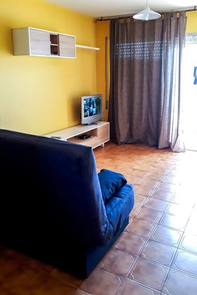 Vue du coin salon avec télévision et accès direct à la terrasse.